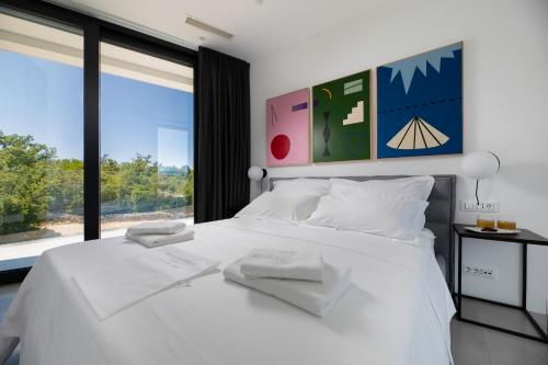 a bedroom with a white bed with a large window at Villa Bianca in Vantačići