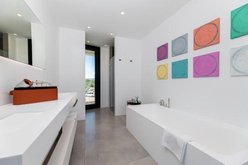 a bathroom with white counters and colorful paintings on the wall at Villa Bianca in Vantačići