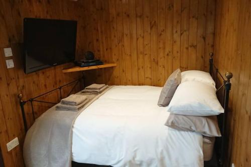 Malthouse Farm Cottage Carriage في Dilhorne: غرفة نوم مع سرير وتلفزيون على الحائط