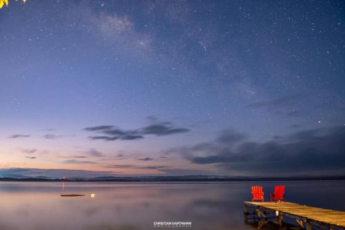 a dock with two chairs on the water at night at Hotel Gringo Perdido in El Remate