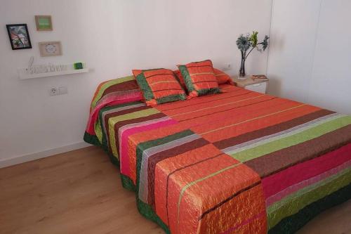 1 dormitorio con 1 cama con una manta y almohadas coloridas en Aitana, en Fortaleny