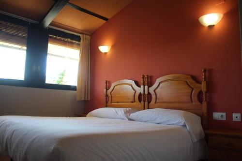 two beds in a bedroom with red walls and two windows at Hotel De Jerica in Jérica