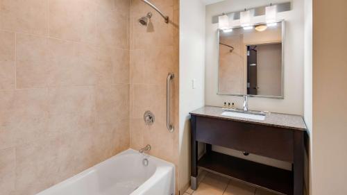 a bathroom with a tub and a sink and a mirror at Best Western Plus Atrium Inn & Suites in Clarksville