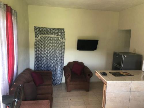 a living room with two chairs and a couch and a television at ApartmentsWestvillage 2bedroom in Montego Bay