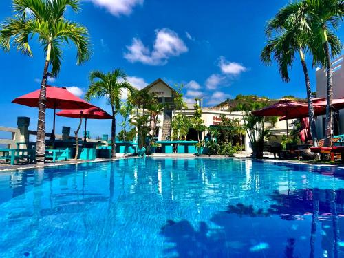 a large swimming pool with palm trees and a building at Mui Ne Hills Bliss Hotel in Mui Ne