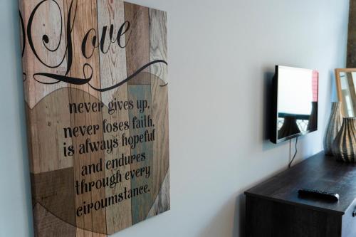 a wooden wall with a sign that says love never gives up never losses faith at Sunrise - Casa Sao Joao - 4 Star Tourist Apartments in Angra do Heroísmo