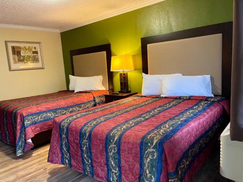 2 camas en una habitación de hotel con paredes verdes en Economy Motel en Galloway
