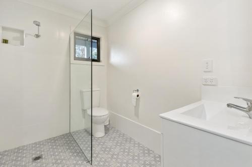 a white bathroom with a toilet and a sink at Avalon Farm Stay in The Rock