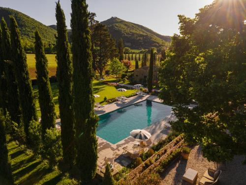 een uitzicht over een zwembad in een tuin met bomen bij Villa di Piazzano - Small Luxury Hotels of the World in Cortona