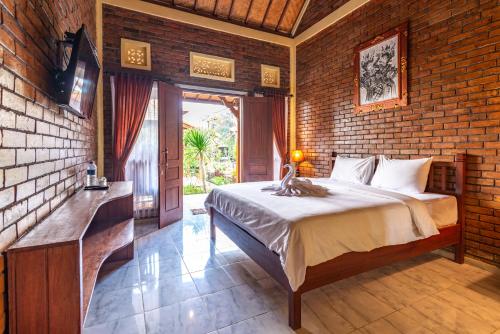 een slaapkamer met een bed en een bakstenen muur bij The Garuda Villa and Restaurant in Bedugul