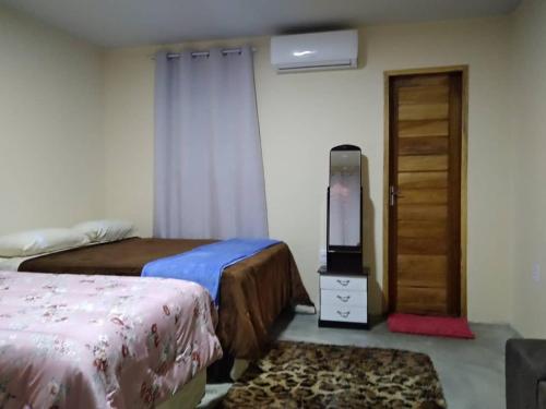 1 dormitorio con 2 camas, TV y puerta en Chalés Serra Monte, en Monte das Gameleiras