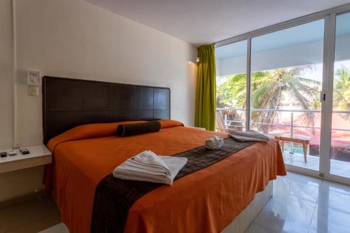 ein Schlafzimmer mit einem Bett mit orangefarbenen Laken und einem großen Fenster in der Unterkunft Kay Hotel in Playa del Carmen