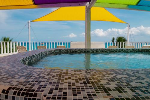 a swimming pool with a colorful umbrella and chairs at Hotel Kay Adults Only in Playa del Carmen