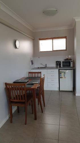a kitchen with a table and two chairs and a refrigerator at Main Street Motel in Hervey Bay