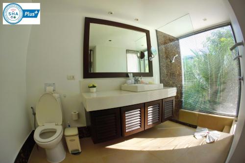 a bathroom with a toilet and a sink and a mirror at Casuarina Shores Apartment - SHA Plus in Bang Tao Beach