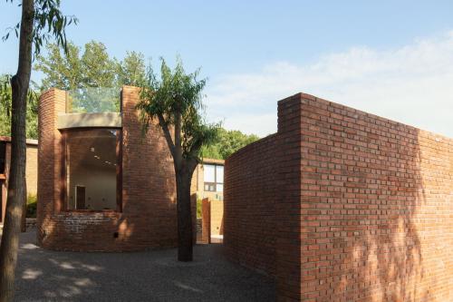 a brick wall with a tree in front of a building at Brickyard Retreat at Mutianyu Great Wall Adjoin to Mutianyu Great Wall - Room with the View of Great Wall - Chinese massage experience - Vehicle Shuttle Service - International Catering - SPA& Nail Beauty Facilities in Huairou