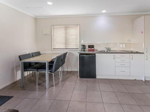 a kitchen with a table and chairs in a room at Cottage Park Thermal Motel in Tauranga