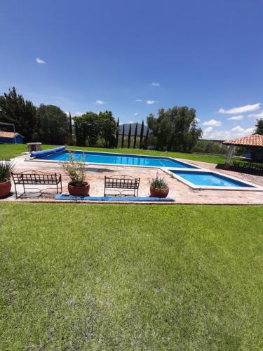 een zwembad met twee banken in een tuin bij Villa Centenario exclusivo Familias in Tequisquiapan