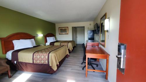 a hotel room with two beds and a desk at Big Spring Inn Madisonville in Madisonville