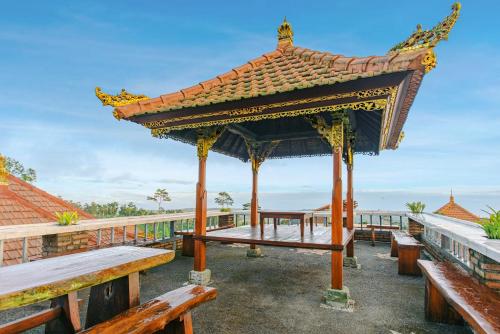 a gazebo with benches in front of the ocean at The Garuda Villa and Restaurant in Bedugul