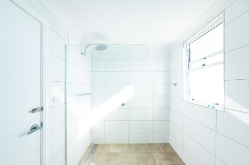 La salle de bains blanche est pourvue d'une douche et d'une fenêtre. dans l'établissement Peel Inn Hotel Nundle, à Nundle