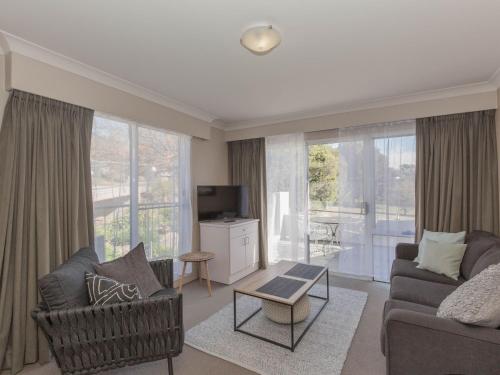 a living room with a couch and a chair and a tv at Horizons 501 in Jindabyne
