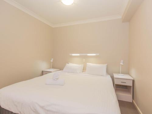 a bedroom with a large white bed with two night stands at Horizons 501 in Jindabyne