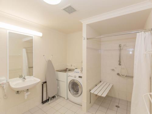 a white bathroom with a washing machine and a sink at Horizons 501 in Jindabyne