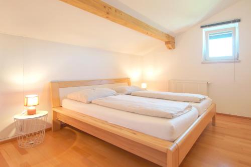 1 dormitorio con cama con marco de madera y ventana en Appartement Unterweger, en Sankt Niklas an der Drau