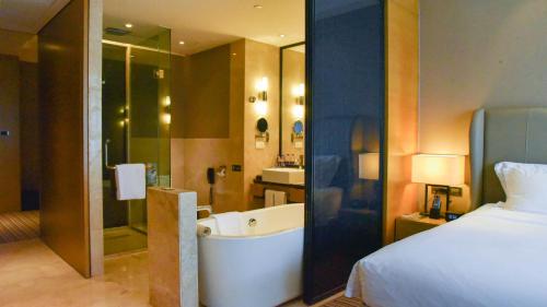 a hotel room with a bed and a bath tub at Pullman Foshan Shunde-Canton Fair Shuttle Bus at Extra RMB100 per Person Daily in Shunde