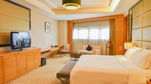 a hotel room with a bed and a television at Pullman Foshan Shunde-Canton Fair Shuttle Bus at Extra RMB100 per Person Daily in Shunde