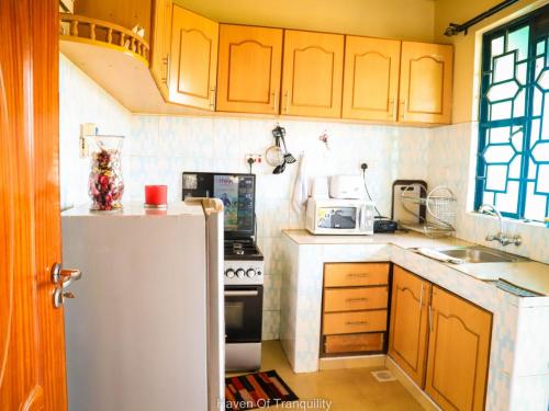 a kitchen with a white refrigerator and a stove at Stay.Plus Milimani Apartment Kisumu in Kisumu