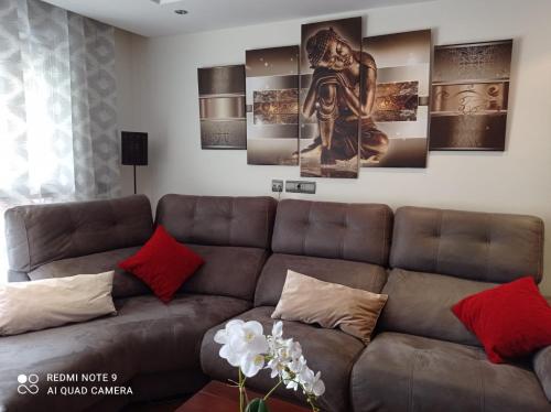 a living room with a brown couch and some paintings at Amplio apartamento Marbella in Marbella