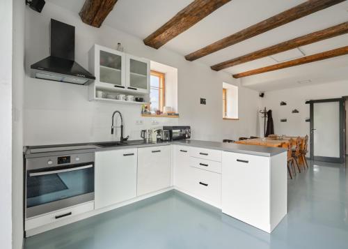 a kitchen with white cabinets and stainless steel appliances at Roubenka U Babi in Lipná