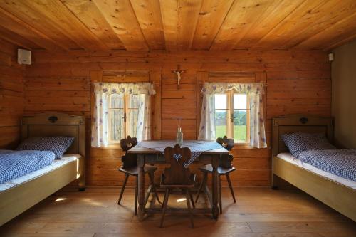 a room with two beds and a table in a cabin at Roubenka U Babi in Lipná
