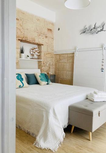 a white bedroom with a large bed with blue pillows at Antigua in Monopoli