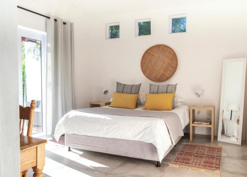 a white bedroom with a bed with yellow pillows at Kogman & Keisie Guest Farm in Montagu