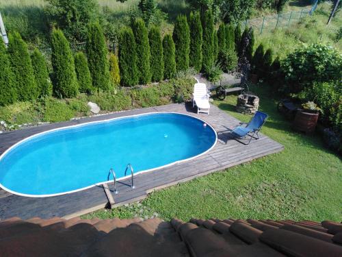 a swimming pool with a deck and a chair next to it at Apartament Zimowa Cisza in Piwniczna-Zdrój