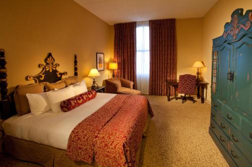 ein Hotelzimmer mit einem großen Bett und einem Stuhl in der Unterkunft Hotel Encanto de Las Cruces in Las Cruces