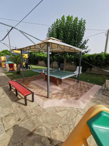 a pavilion with a bench and a table and a swing at Villa Rosa in Modica
