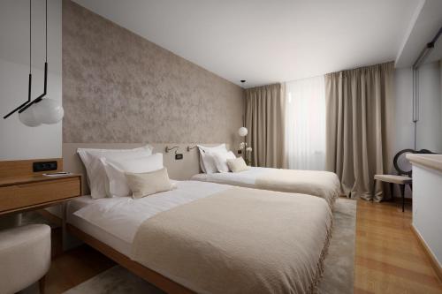 a hotel room with two beds and a desk at Malipiero Residence in Rovinj