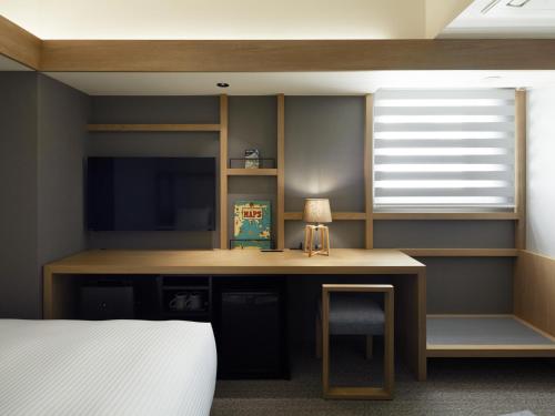 a bedroom with a desk with a tv and a bed at LAMP LIGHT BOOKS HOTEL sapporo in Sapporo