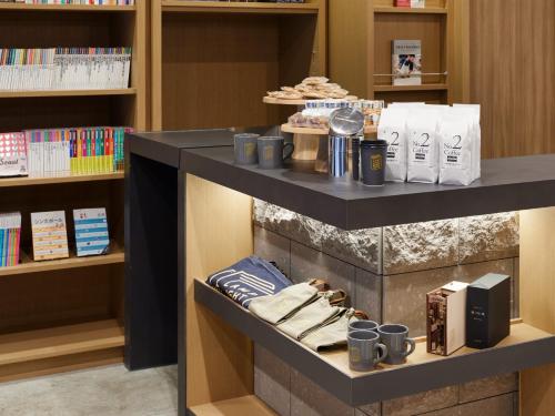 a shelf with cups and books in a library at LAMP LIGHT BOOKS HOTEL sapporo in Sapporo