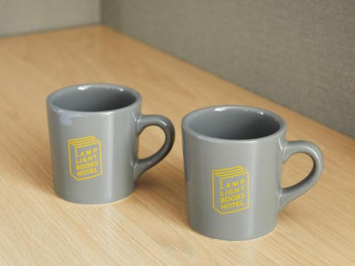 two coffee cups sitting on top of a table at LAMP LIGHT BOOKS HOTEL sapporo in Sapporo
