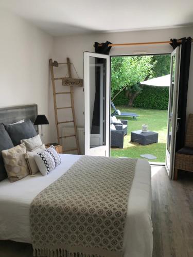 a bedroom with a bed and a sliding glass door at La Maison des Eaux Claires in Puymoyen