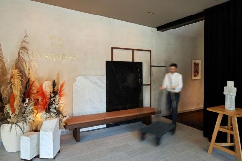 a man standing next to a bench in a room at L'Esquisse Hotel & Spa Colmar - MGallery Collection in Colmar