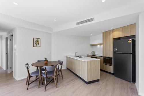 a kitchen with a table and a black refrigerator at Pinnacle on the Park in Gold Coast
