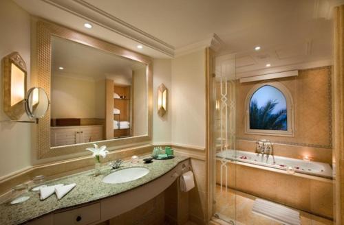 a bathroom with a sink and a tub and a mirror at Kempinski Hotel Soma Bay in Hurghada