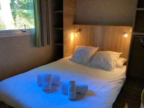 Una cama blanca con dos toallas azules. en Domaine du Lac en Soursac