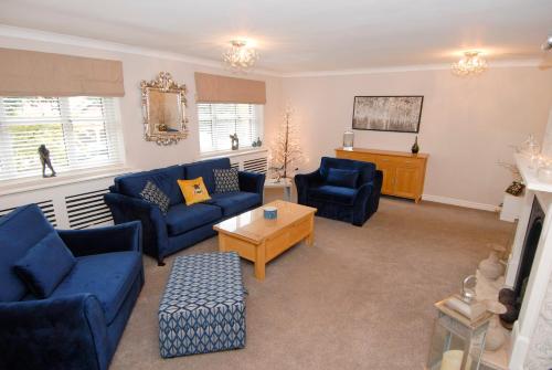 a living room with blue couches and a tv at Wilmslow Airbnb in Wilmslow